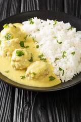 Boller i Karry Pork Meatballs in mild Curry with rice close up in the plate on the table. Vertical