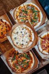 Close-up of Margarita pizza in a disposable dish. Top view of takeaway food in a fast food cafe. On photo - mozzarella cheese, tomatoes, and red basil. The classic recipe. Food for family and friends.