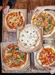 Close-up of Margarita pizza in a disposable dish. Top view of takeaway food in a fast food cafe. On photo - mozzarella cheese, tomatoes, and red basil. The classic recipe. Food for family and friends.