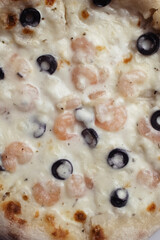 Close-up of pizza with shrimps. Seafood and vegetarian food. Italian food in restaurants and cafes. The concept of marine ingredients in meal preparation.