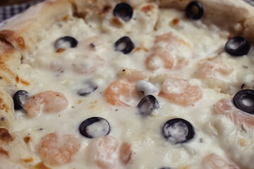 Close-up of pizza with shrimps. Seafood and vegetarian food. Italian food in restaurants and cafes. The concept of marine ingredients in meal preparation.