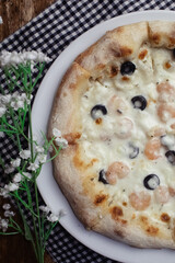 Close-up of pizza with shrimps. Seafood and vegetarian food. Italian food in restaurants and cafes. The concept of marine ingredients in meal preparation.