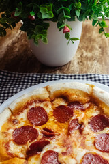 Pepperoni pizza close up. A dish covered with sausage rings and herbs. Italian cuisine in restaurants and cafes. The concept of meat ingredients in cooking.