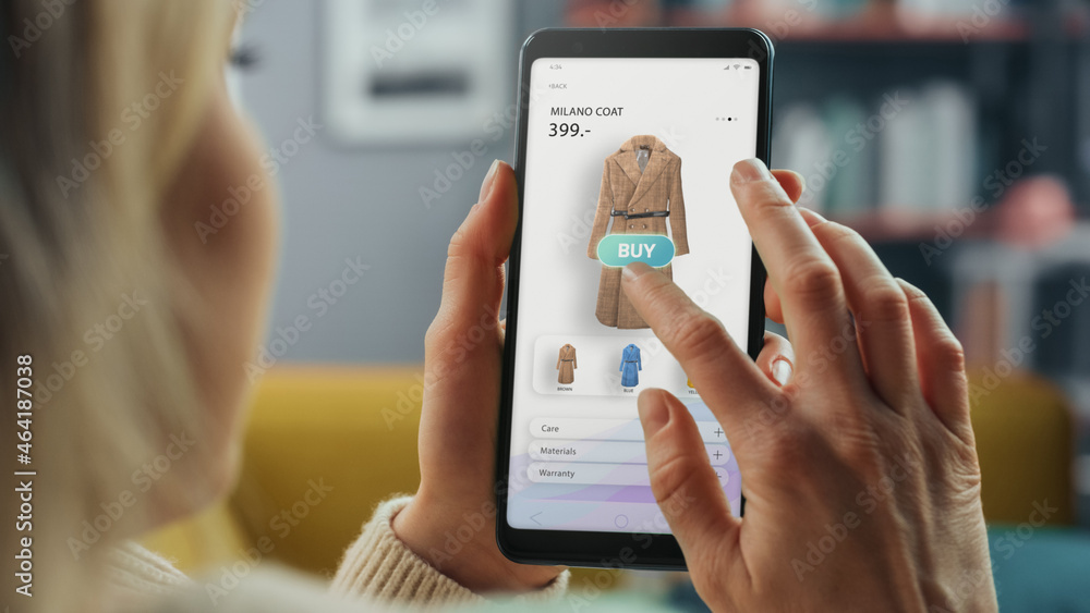 Aufkleber beautiful caucasian female is using smartphone with clothing online web store to choose and buy coat