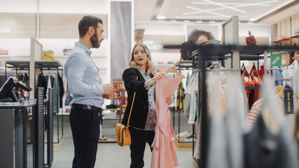 Beautiful Female Customer Shopping in Clothing Store, Retail Sales Associate Helps with Advice. Diverse People in Fashionable Shop, Choosing Stylish Clothes, Colorful Brand with Sustainable Designs