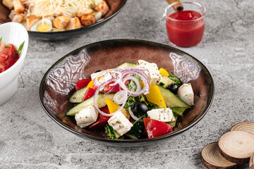 Portion of fresh greek salad with cheese and vegetables on gray backgound