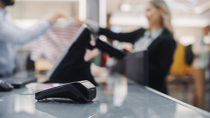 Clothing Store: Close-up shot of a Ready Contactless NFC Terminal. Trendy Fashion Shop with Stylish Designer Brands in the Background.