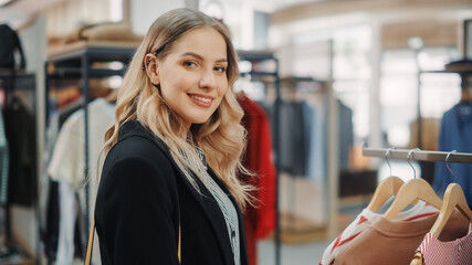 Beautiful Smiling Female Customer Shopping in Clothing Store, Choosing Stylish Clothes, Blouse, Shirt, Looking at Camera. Girl in Fashionable Brands Shop Sustainable Designs. Close-up Portrait