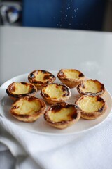 Egg tart, traditional Portuguese dessert, pastel de nata, pasteis on a plate. Grey stone background.
