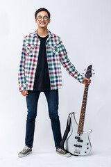 Full-body portrait shot of handsome young teenage musician holding a bass guitar in the studio....