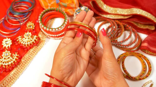 A lady wearing red bangles while getting ready to go out. Handmade bangles  a white necklace  and an Indian traditional dress kept together - luxury  lifestyle  pretty  craftswoman 