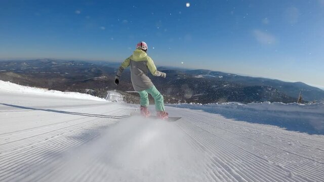 SLOW MOTION: a girl on a snowboard rides in the morning on fresh corduroy on a ski track. second-person view, camera pursuit. the concept of active recreation in winter. 2k prores