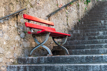 Red bench placed in the middle of a stone stair way in Lugano Switzerland