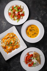 Delicious autumn table setting with pumpkins. Healthy food, close-up in a white plate on dark stone. Autumn dishes for Halloween. Thanksgiving dinner background with turkey and all sides dishes