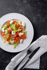 Fresh baked pumpkin salad with tomato, pumpkin seeds, Peking cabbage, feta cheese and vegetable dressing. Healthy food, vegetarian dieting, close up on dark background