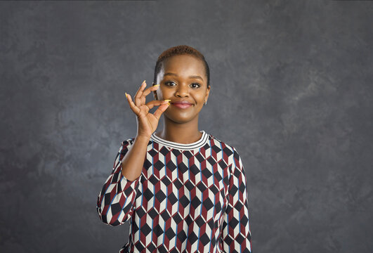 My Lips Are Sealed. Won't Tell Anyone, I Swear. Studio Headshot Of Happy Young Black Woman Doing Lip Zip Gesture Promising To Keep Silent, Not Reveal Your Secret Or Telling She Can't Share Information