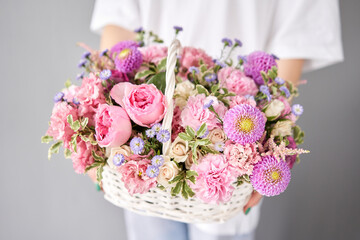 Flower arrangement in Wicker basket. Beautiful bouquet of mixed flowers in woman hand. Handsome fresh bouquet. Small flower shop and Flowers delivery.