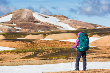 Happy female hiker with backpack enjoying the landscape of Iceland while hiking the Laugavegur trail. Travel, sport, lifestyle concept