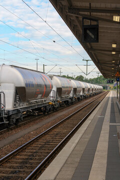 Perspective view of Holcim cement train tanks transit at Itzehoe train station in summer with clouds in blue sky background. No people.