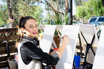 beautiful young woman smiling and looking at camera in art class painting