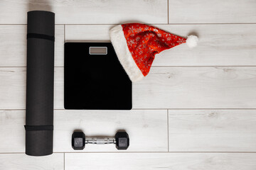 Black weigher, mat and dumbbell on gray wooden background. Christmas concept