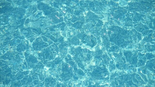 Sparkling waters swaying in a swimming pool with light-blue waves in summer  
