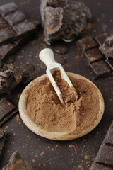 Cacao powder in wooden bowl with chopped and chips of  dark chocolate
