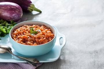 Eggplant caviar in blue bowl and fresh vegetables on background