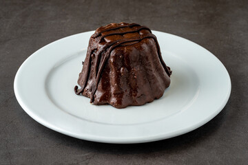 Chocolate souffle on white porcelain plate on dark stone table
