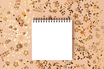 Empty notebook mockup with glittering gold confetti on a beige background.