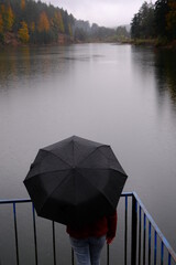 woman holding umbrella under rain by the lake