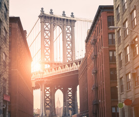 Obraz premium Dumbo at sunset with the sun coming down behind the bridge. New York City Skyline. High quality photo