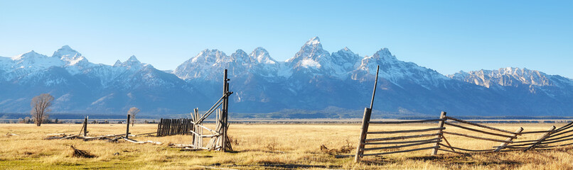 Old broken wooden fence on a field with Teton mountain range in background, Wyoming, USA.