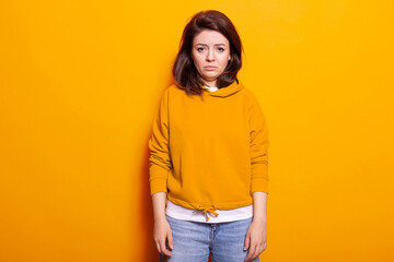 Portrait of young adult feeling sad and disappointed on camera. Distraught woman showing facial expression of frustration and depression. Unhappy person posing with expressive face.