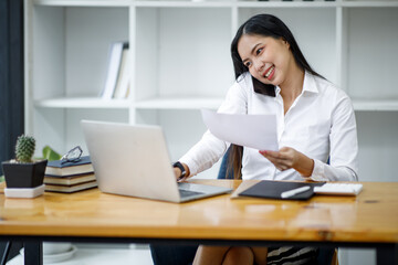 Portrait of Asian young female Businesswoman working on laptop computer doing finances,accounting analysis,report,data and pointing graph at the office.