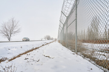 Barbed wire fence on border in winter. Private secured object near highway. Maximum security...