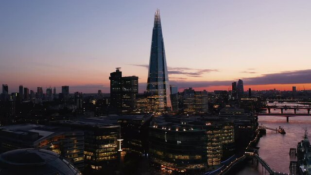 Forwards fly above evening city. Heading towards Shard skyscraper. Modern tall office building against colourful twilight sky. London, UK