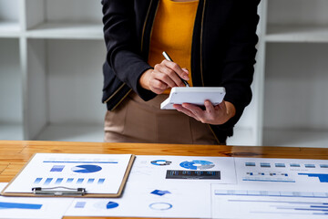 Close up Business woman using calculator and laptop for do math finance on wooden desk, tax, accounting, statistics and analytical research report concept