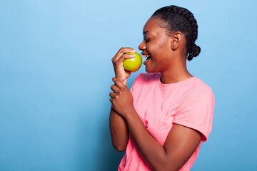 Portrait of african american teenager enjoying fruits with vitamins eating nutrition green apple...