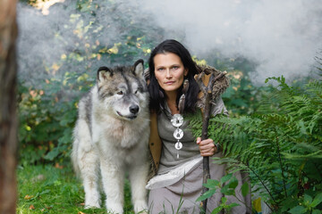 Forest dweller woman with a large dog Alaskan Malamute in the forest