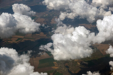 Aerial view from airplane window of white puffy clouds on bright sunny day.