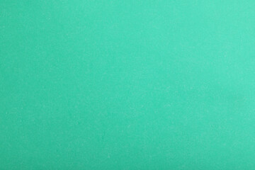 Abstract green paper background. Blank wrapping paper or shiny cardboard for a decorative design element. Grainy surface. 