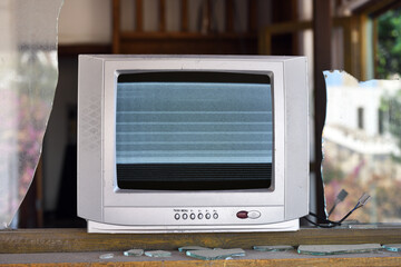 An old silver TV with clutter on the screen in an abandoned hotel. Vintage TVs 1980s 1990s 2000s. 