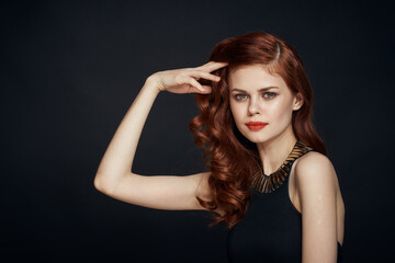 attractive red-haired woman in a black dress hairstyle dark background