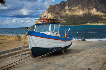 old fishing boat at Cornino Bay in Sicily Trapani with blue sky and many clouds threaten