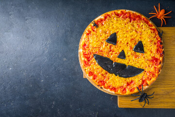 Halloween party trick or treat food, funny scary pizza in the style of Halloween characters - bats, spiders, jack o lantern pumpkin, cheddar, mozzarella and black cheese