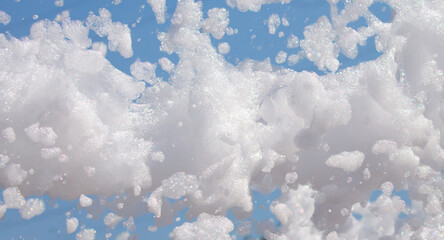 White soap foam on a blue sky background. Fun foam, background or texture of a white foam with copy space Entertainment foamy parties a summer entertainment festival in the water park