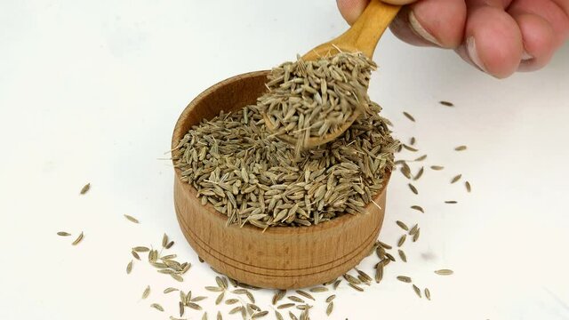 Chef taking chopped dry cumin seeds or zira spices from wooden spice jar. Close-up.