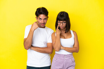 Young mixed race couple isolated on yellow background looking to the front
