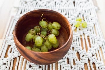 geren grapes in wooden bowl on top of wooden dining table, simple ingredients concept